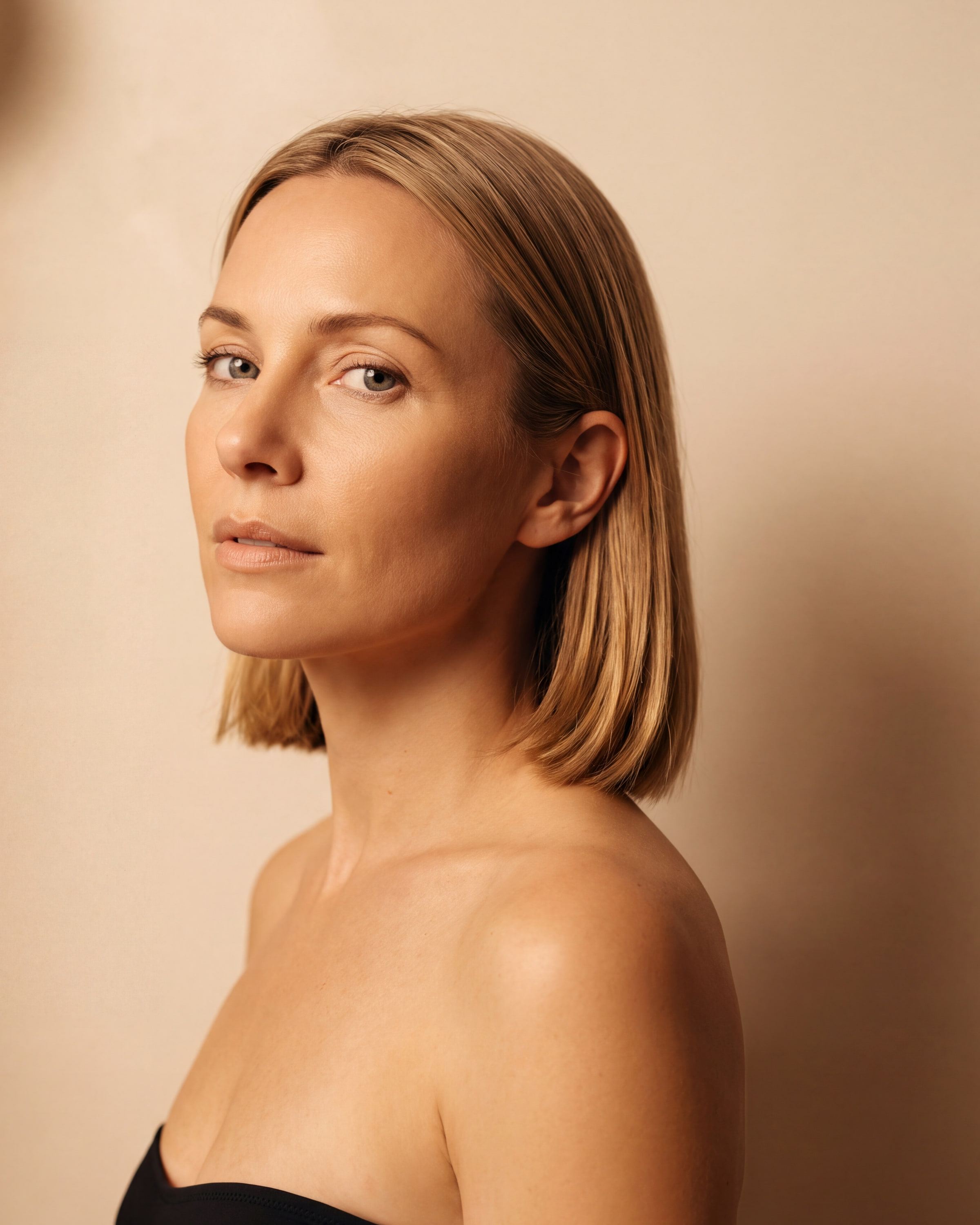 AI rendering: the same woman with light skin after a soft golden custom spray tan